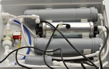 Reverse osmosis system installed under sink with filters, tubing, and water lines connected